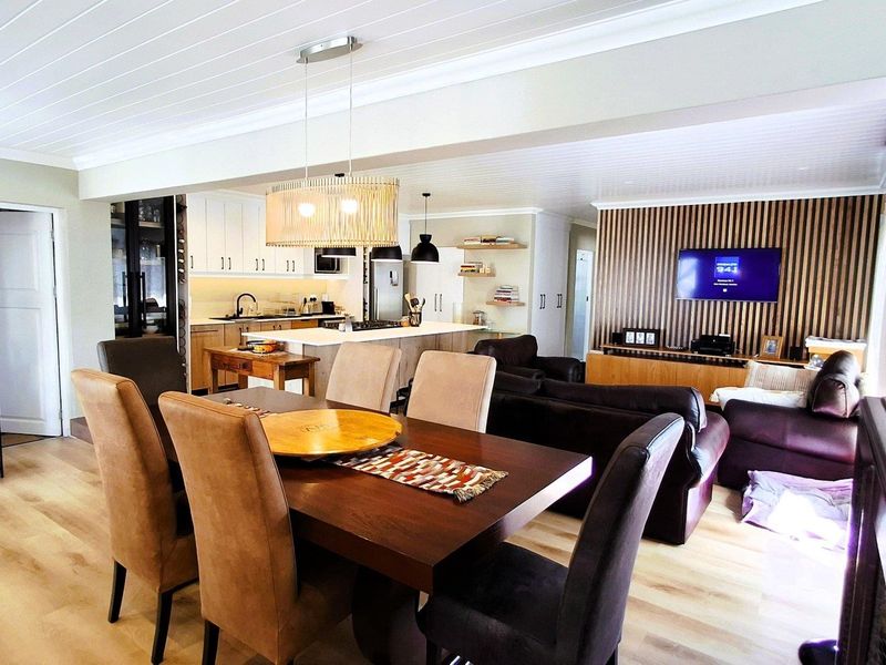 Spacious open-plan living and dining area featuring a modern kitchen with island, timber slat feature wall, and light wood-look flooring.