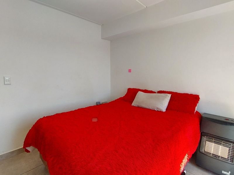 A simple bedroom featuring tiled flooring and neutral white walls, providing a functional and blank canvas for personalization.