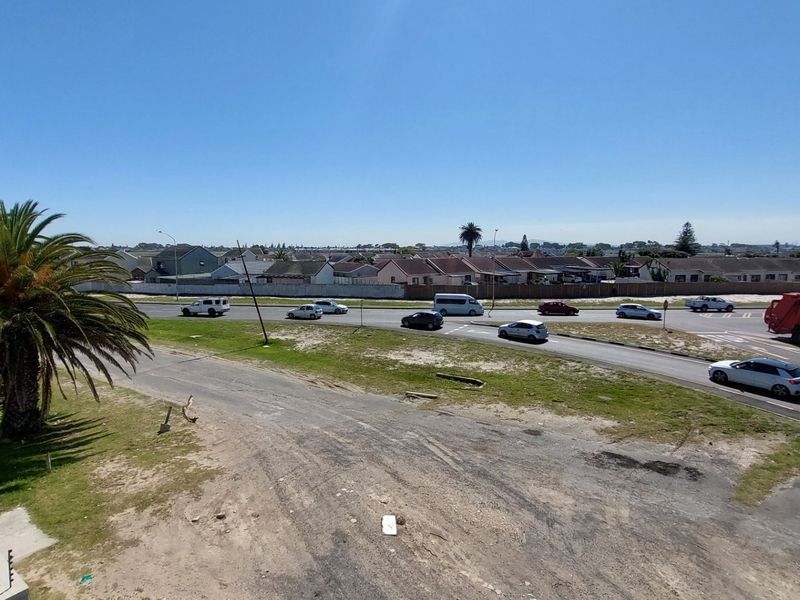 Elevated view overlooking a suburban street, surrounding residential neighborhood, and open land area.