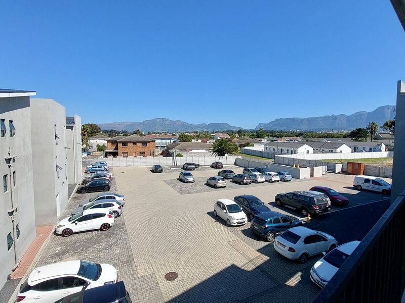 Elevated view overlooking the apartment complex parking area with mountain views in the background.