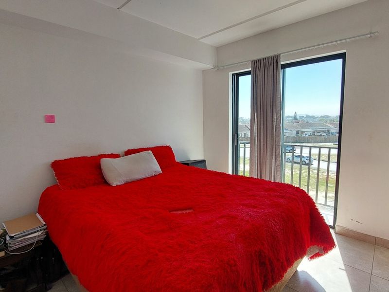 A bedroom featuring tiled flooring, a built-in wardrobe, and a sliding glass door providing access to a balcony with exterior views.