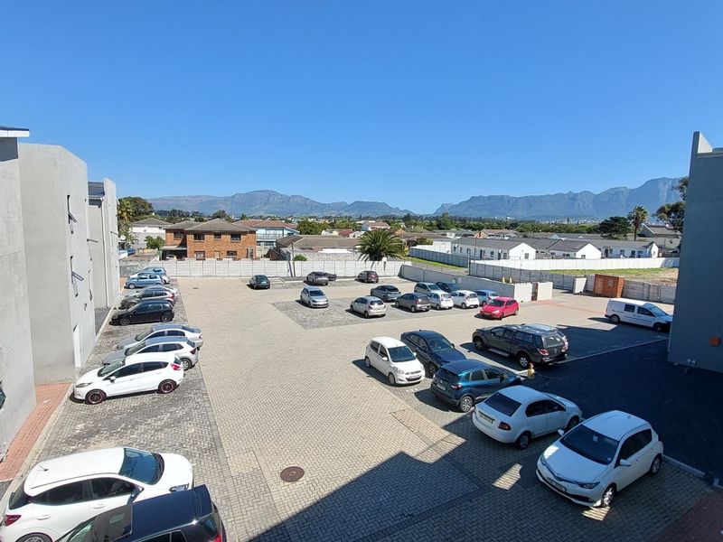 Elevated view overlooking the apartment complex parking area with mountain vistas in the background.
