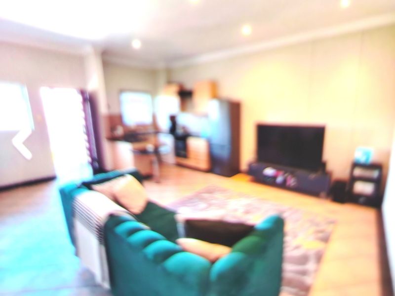 An open-plan living and kitchen area featuring tiled flooring and recessed lighting, presented in a blurry, low-quality photograph.