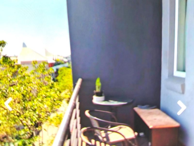A compact balcony featuring a metal safety railing and a view of the surrounding neighborhood.