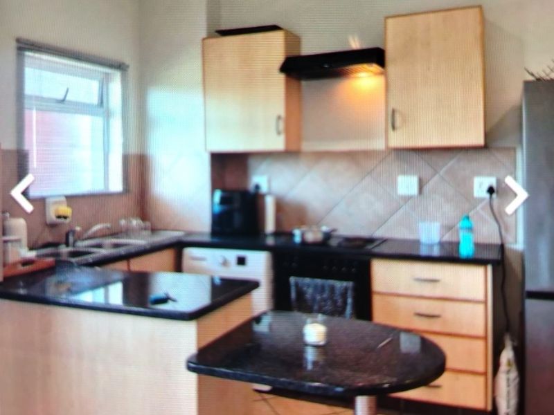 A functional kitchen featuring light wood cabinetry, dark granite countertops, a breakfast nook, and integrated appliances including an oven and extractor fan.