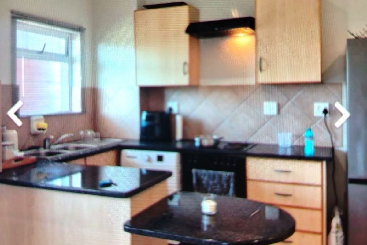 A functional kitchen featuring light wood cabinetry, dark granite countertops, a breakfast nook, and integrated appliances including an oven and extractor fan.