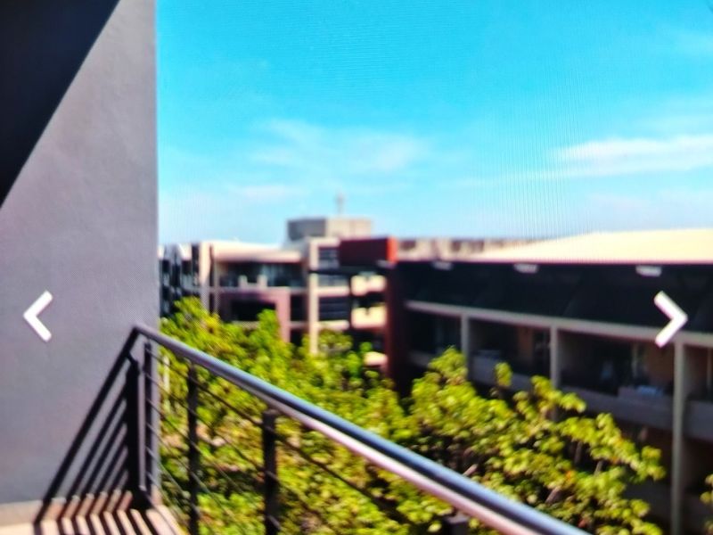 A balcony with a metal balustrade overlooking the surrounding apartment complex and greenery.