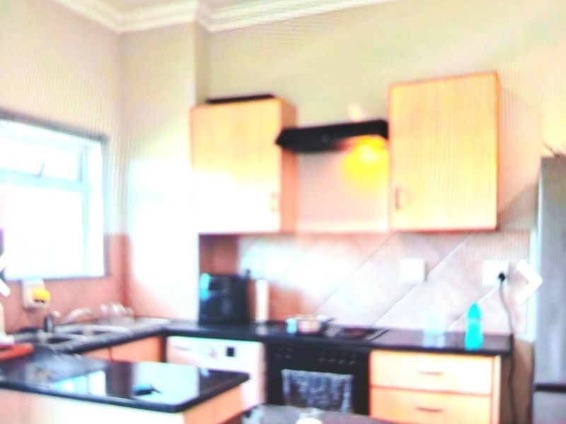 A functional kitchen featuring light wood cabinetry, dark granite countertops, a built-in oven with extractor fan, and a breakfast nook area.