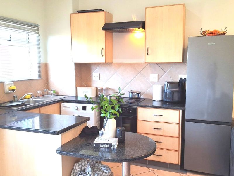 A functional kitchen featuring laminate cabinetry, granite countertops, a tiled backsplash, and a breakfast nook, providing a practical layout for daily meal preparation.