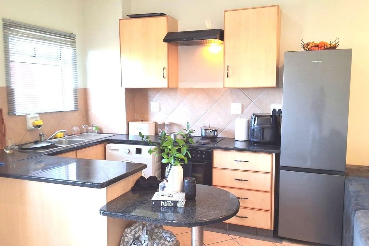 A functional kitchen featuring laminate cabinetry, granite countertops, a tiled backsplash, and a breakfast nook, providing a practical layout for daily meal preparation.
