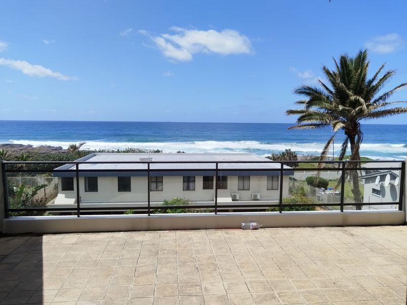 A spacious balcony featuring tiled flooring and a metal balustrade, offering expansive, unobstructed views of the ocean and coastline.
