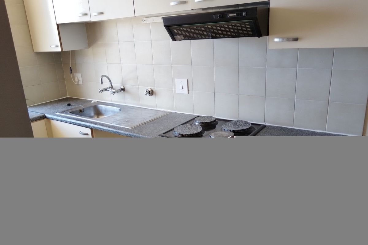 A functional kitchen featuring laminate cabinetry, a stainless steel sink, tiled backsplash, and a built-in electric hob with an extractor fan.