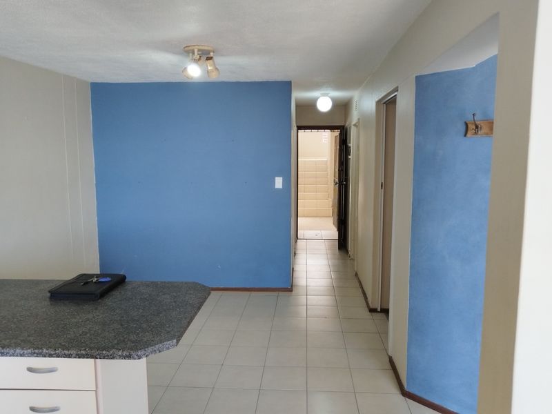 Open plan living area featuring tiled flooring, a granite kitchen countertop, and direct access to the hallway and entrance.