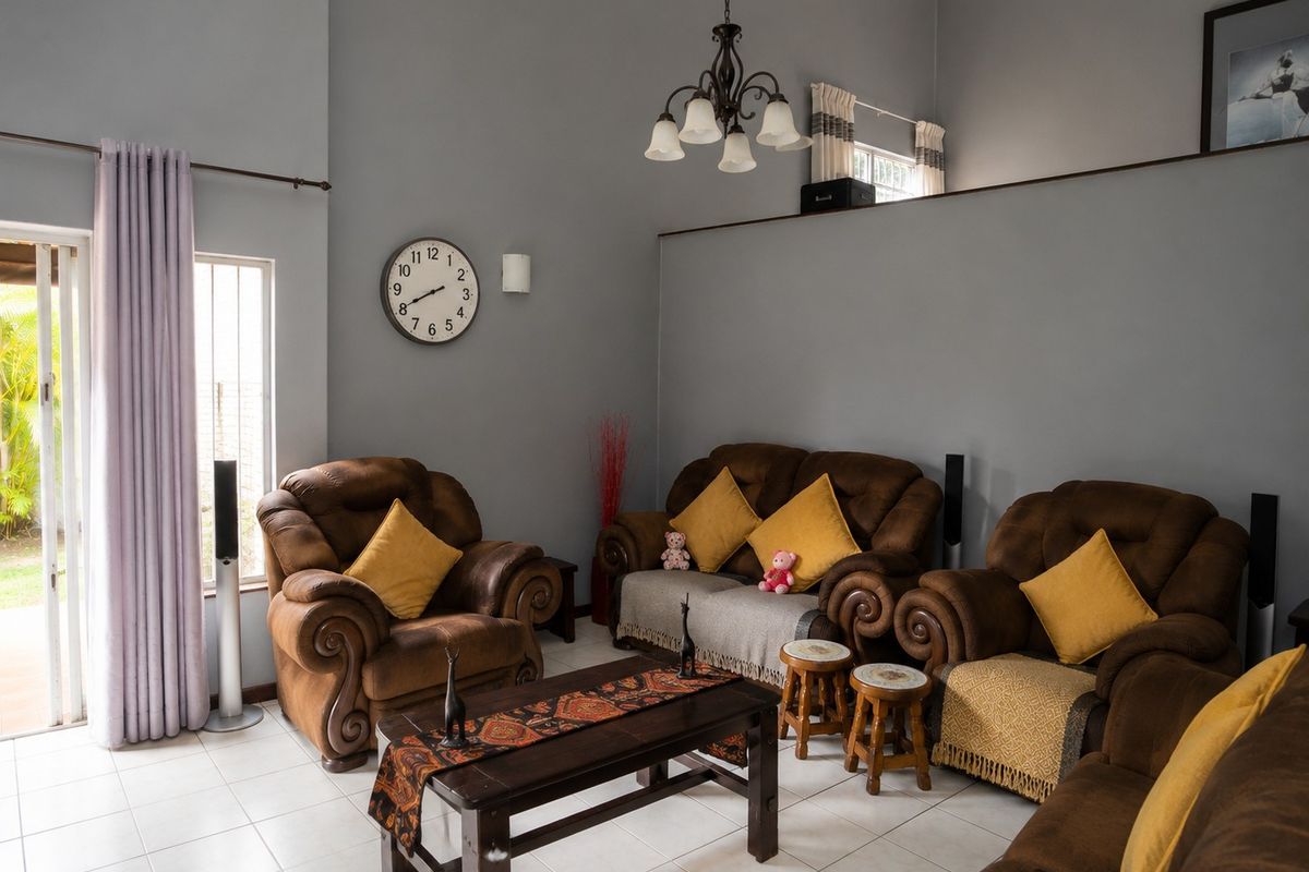 A spacious living room featuring high vaulted ceilings, neutral tiled flooring, and a sliding glass door providing access to the outdoor area.