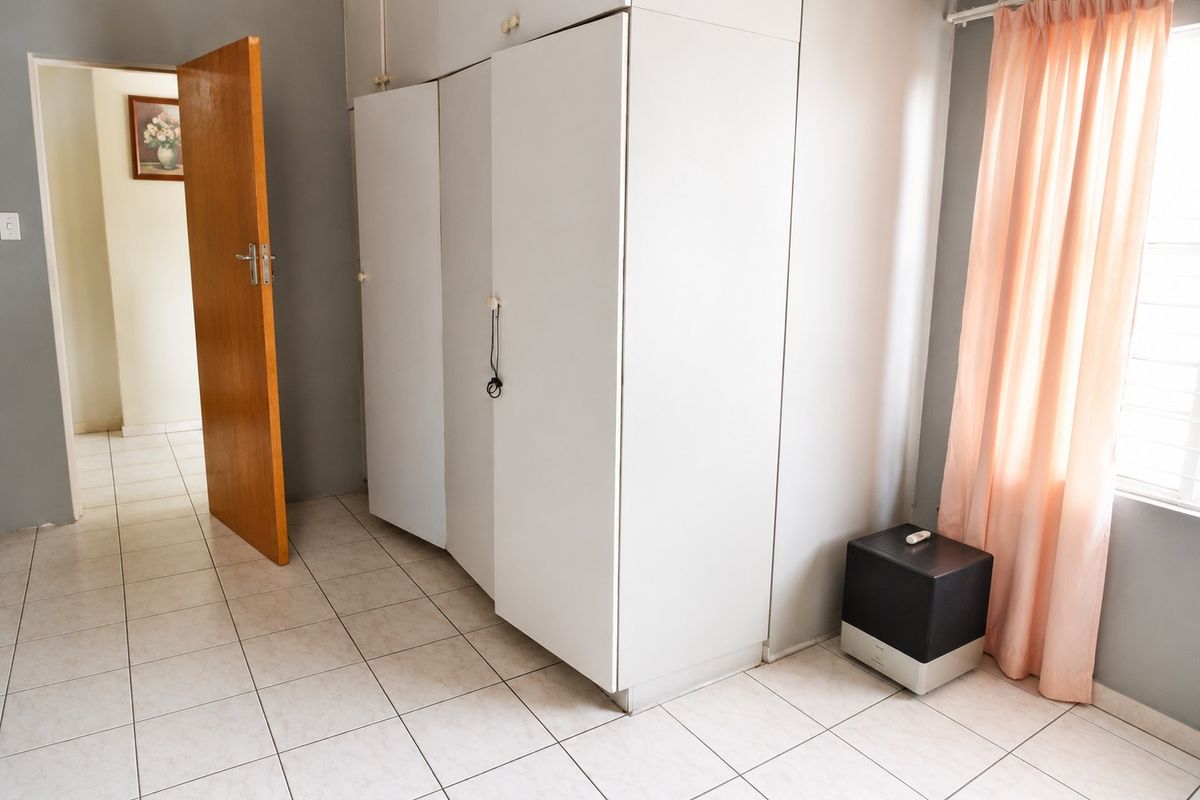 A bedroom featuring built-in cupboards, tiled flooring, and a timber door, offering a functional space ready for personalization.