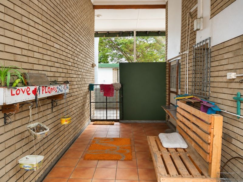 A covered outdoor patio area featuring exposed brick walls and tiled flooring, providing a functional transition space between the interior and exterior.
