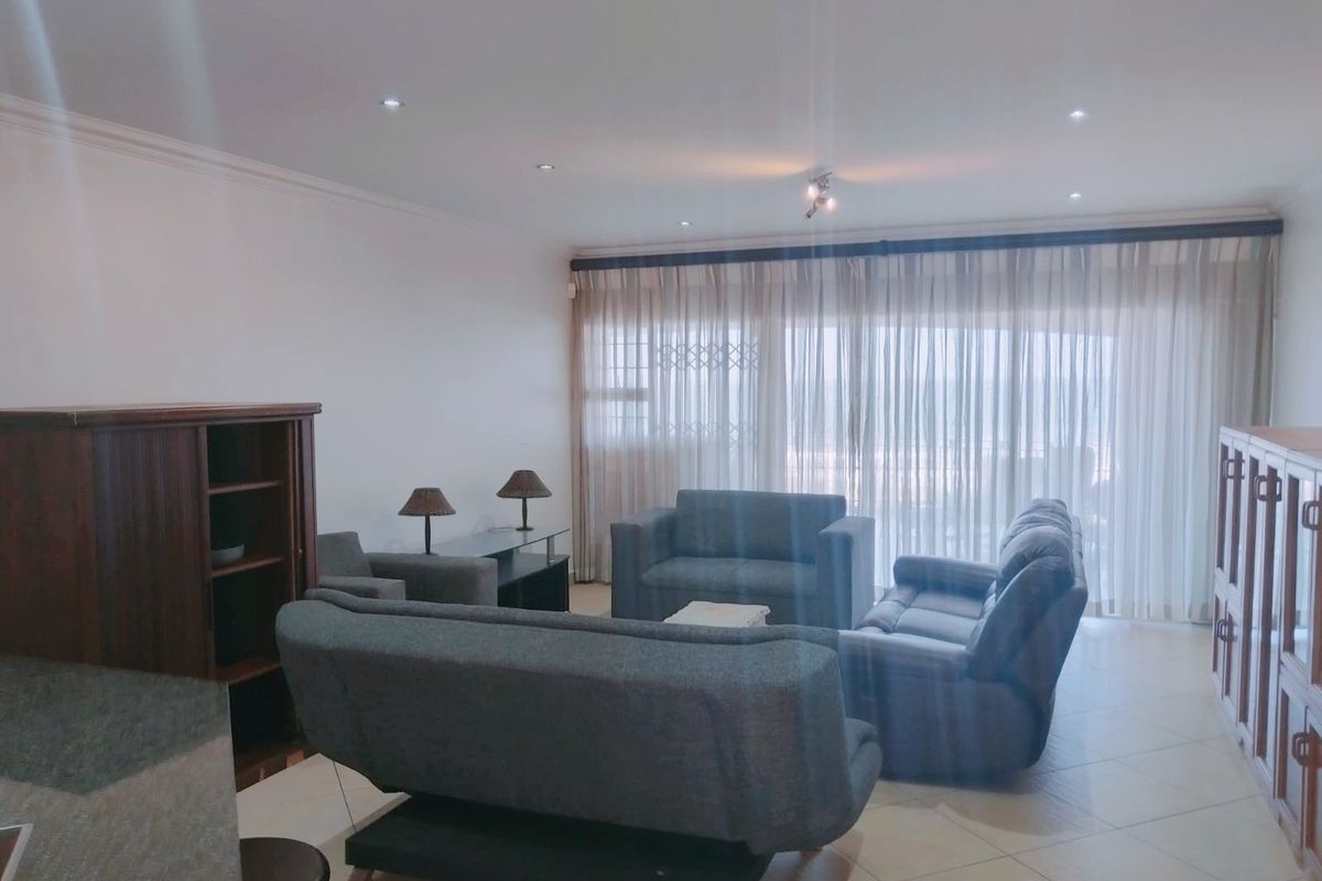 Spacious living room featuring tiled flooring, recessed downlights, and large sliding glass doors with curtains leading to an outdoor area.