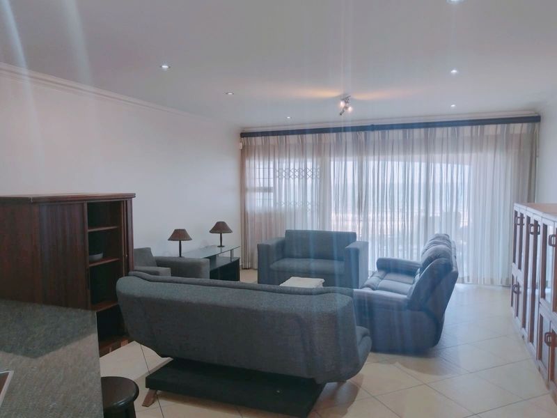 Spacious living room featuring tiled flooring, recessed downlights, and large sliding glass doors with curtains leading to an outdoor area.
