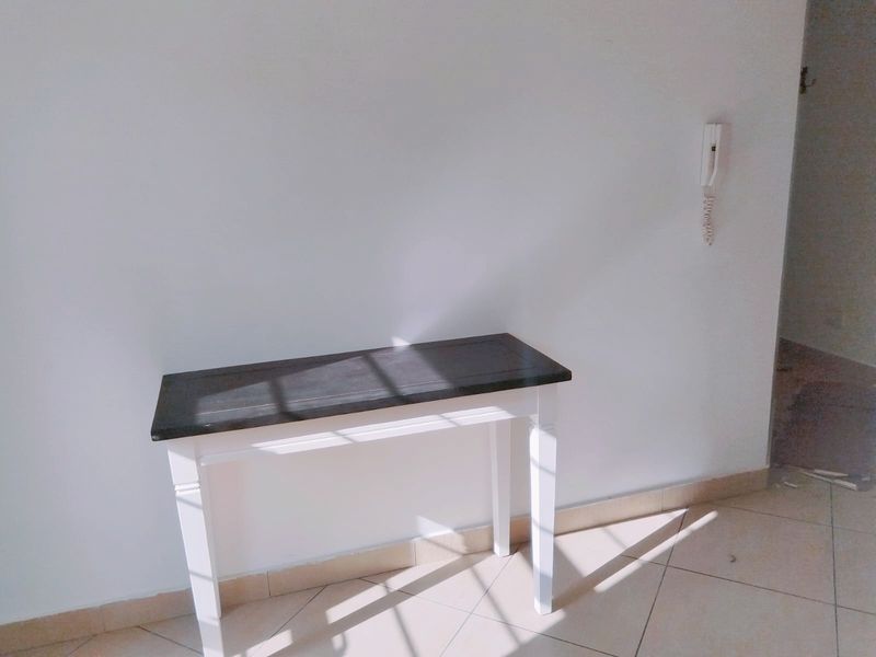 A simple entry area featuring tiled flooring and a wall-mounted intercom system, providing a clean and functional space.