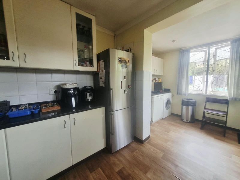 Functional kitchen featuring laminate cabinetry, stone countertops, and a dedicated laundry area with integrated plumbing, offering a practical layout for daily use.