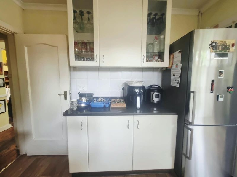 A functional kitchen area featuring white built-in cabinetry, a dark countertop, and a tiled backsplash, providing practical storage and workspace.