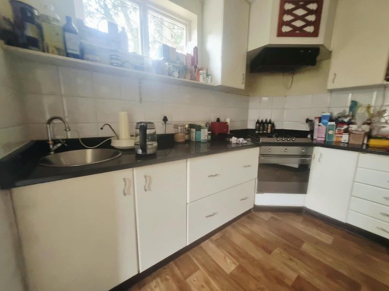A functional kitchen featuring built-in cabinetry, stone countertops, a stainless steel sink, and integrated cooking appliances with a tiled backsplash.