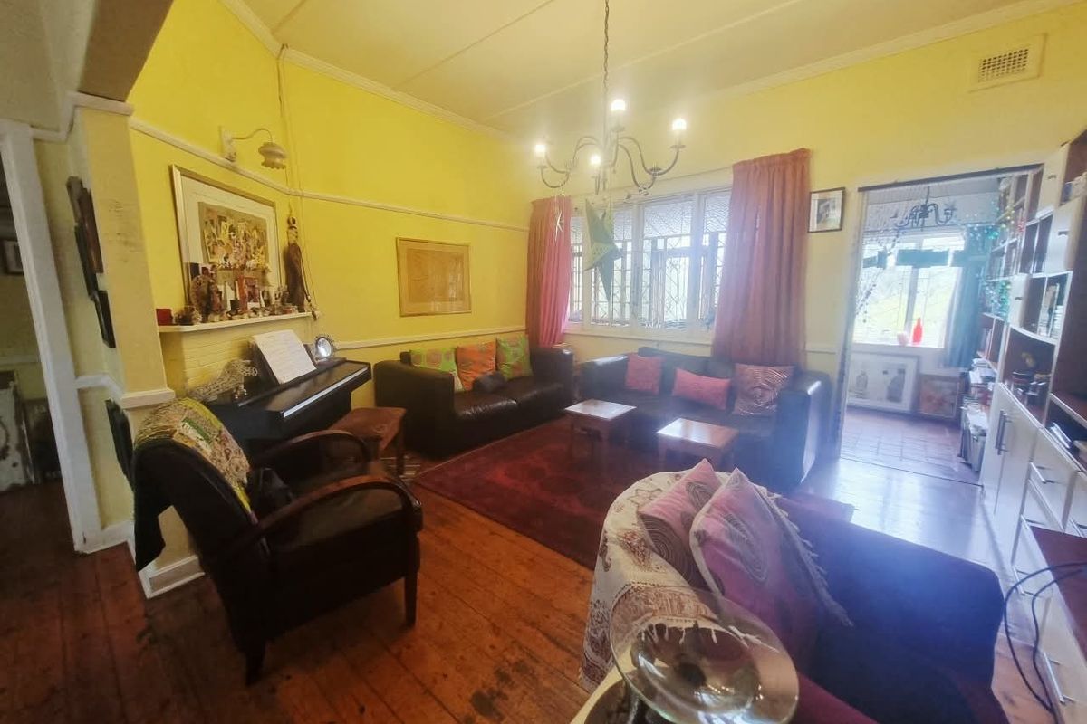 A traditional living room featuring original hardwood flooring, a fireplace mantel, and built-in shelving, offering a classic layout with potential for modernization.