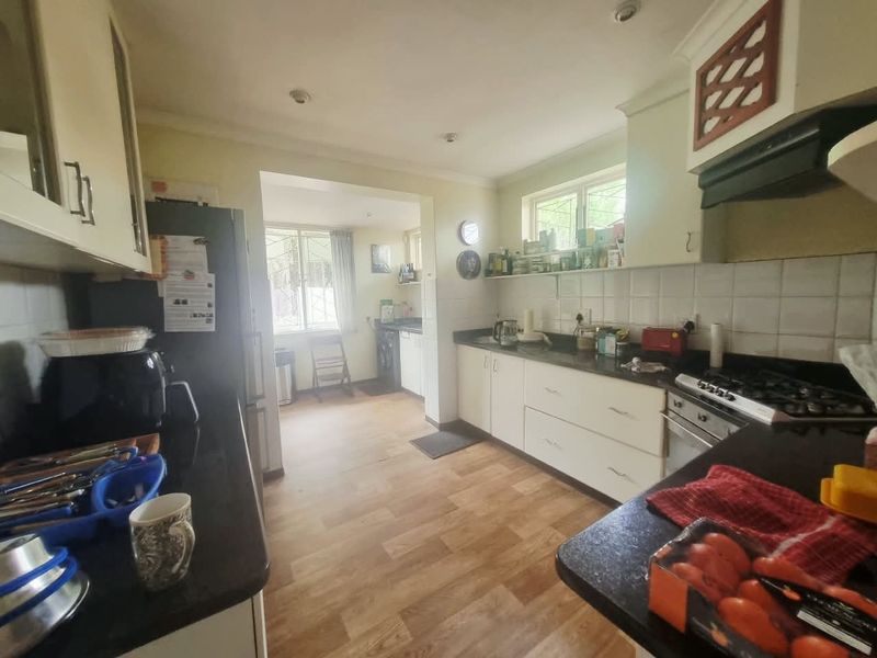 A functional kitchen featuring built-in cabinetry, granite countertops, a gas hob with extractor fan, and a separate scullery area with additional workspace.