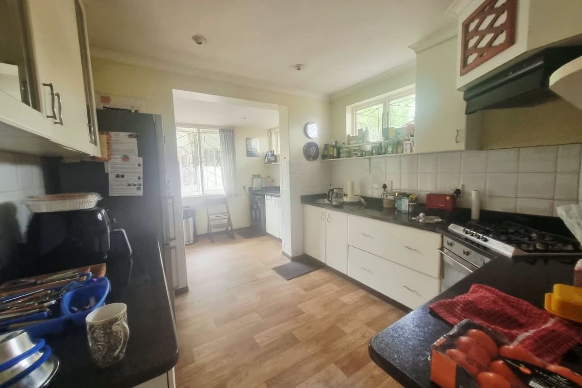 A functional kitchen featuring built-in cabinetry, granite countertops, a gas hob with extractor fan, and a separate scullery area with additional workspace.