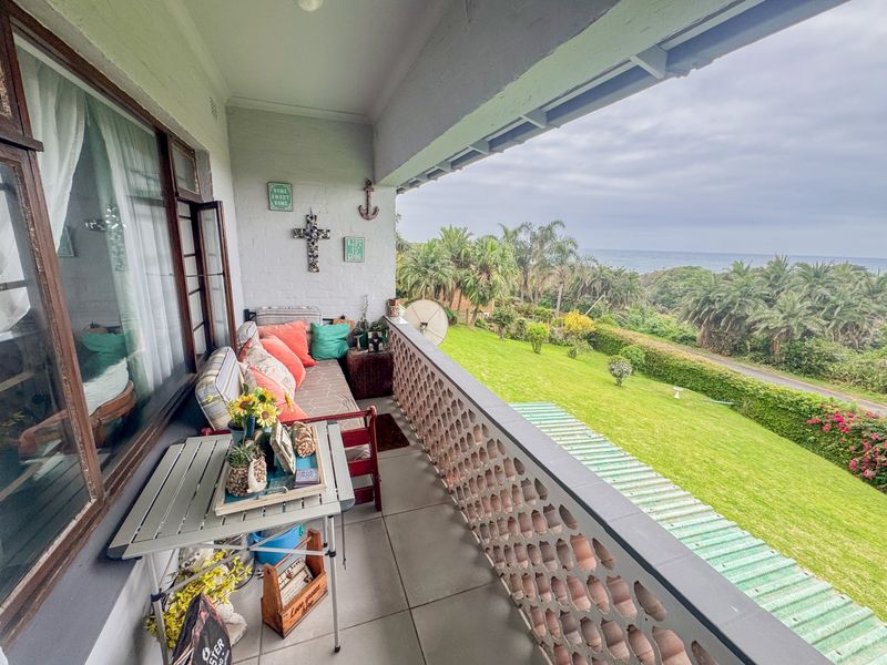 Covered balcony featuring a decorative breeze block balustrade and scenic views over the garden and coastline.