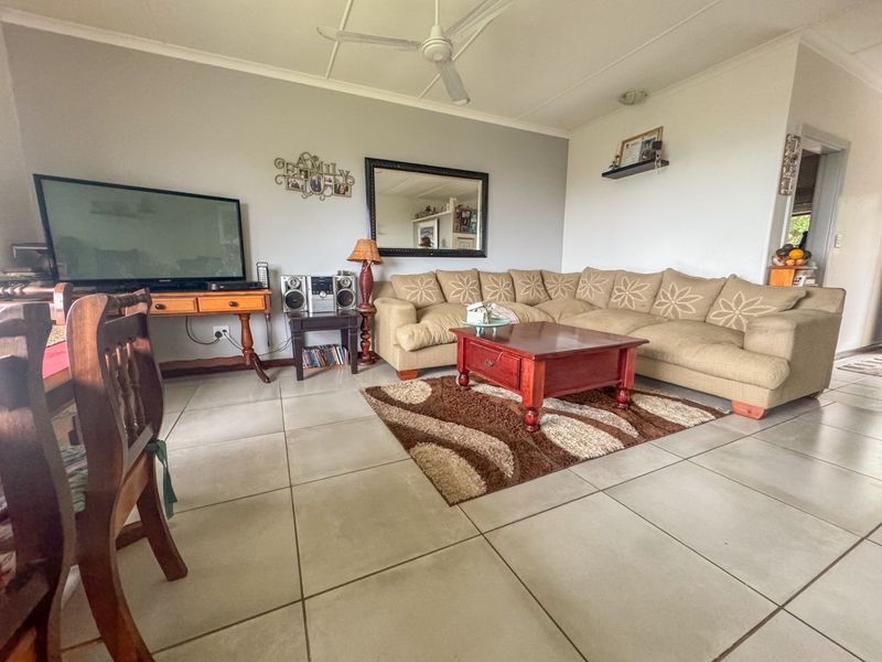 A spacious living room featuring neutral tiled flooring and a ceiling fan, offering a comfortable and functional layout for relaxation.