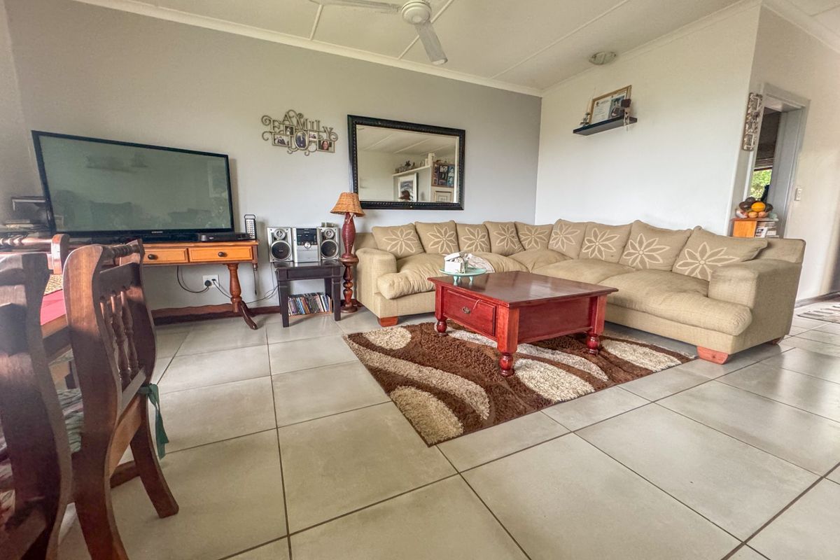 A spacious living room featuring neutral tiled flooring and a ceiling fan, offering a comfortable and functional layout for relaxation.