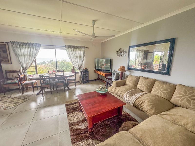 Spacious open-plan living and dining area featuring tiled flooring, a ceiling fan, and large sliding glass doors that provide natural light and outdoor views.