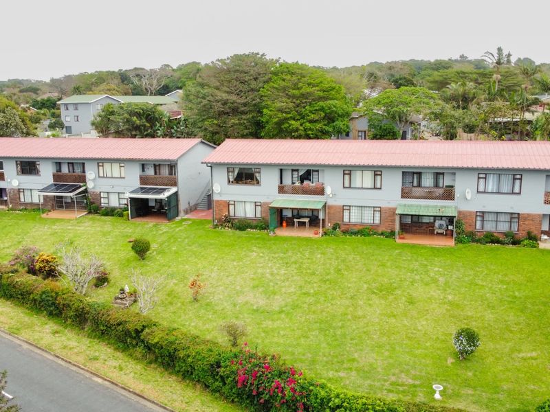 Aerial view of a multi-unit apartment complex featuring metal roofing, brick and painted facades, and shared garden spaces.