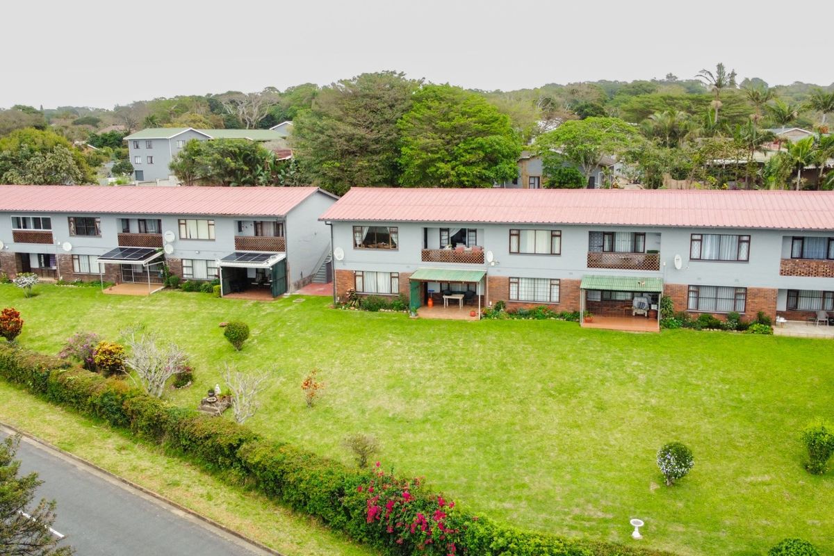 Aerial view of a multi-unit apartment complex featuring metal roofing, brick and painted facades, and shared garden spaces.