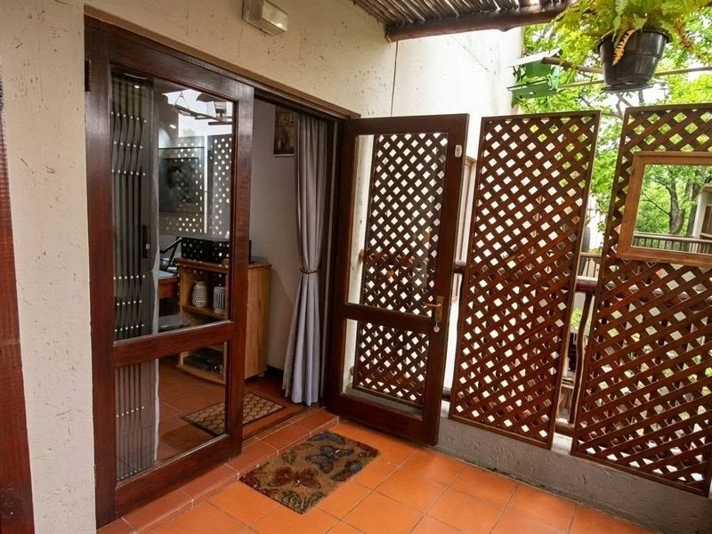 A covered balcony featuring terracotta tiling and a wooden lattice privacy screen, providing a semi-private outdoor transition space.