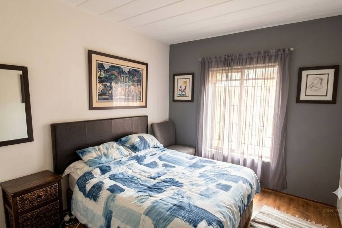 A well-maintained bedroom featuring timber flooring and a window fitted with security bars, providing a comfortable and secure living space.