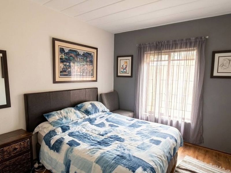 A well-maintained bedroom featuring timber flooring and a window fitted with security bars, providing a comfortable and secure living space.