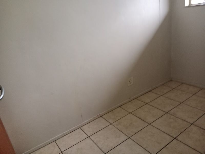 An empty bedroom featuring tiled flooring and a neutral wall finish, ready for personalization.