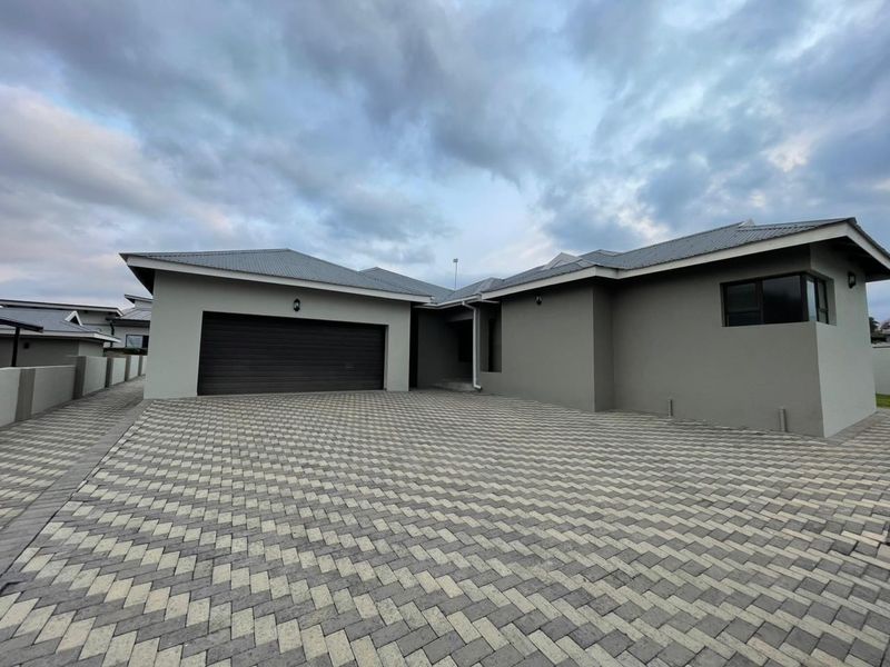 Modern front elevation featuring a spacious paved driveway, automated garage, and clean architectural lines under a pitched roof.