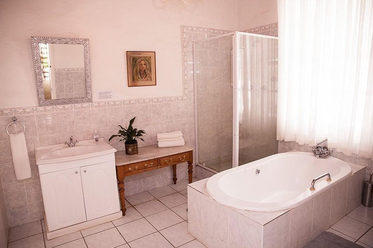 A functional bathroom featuring a built-in bathtub, a separate tiled shower enclosure, and a vanity cabinet with a ceramic basin.