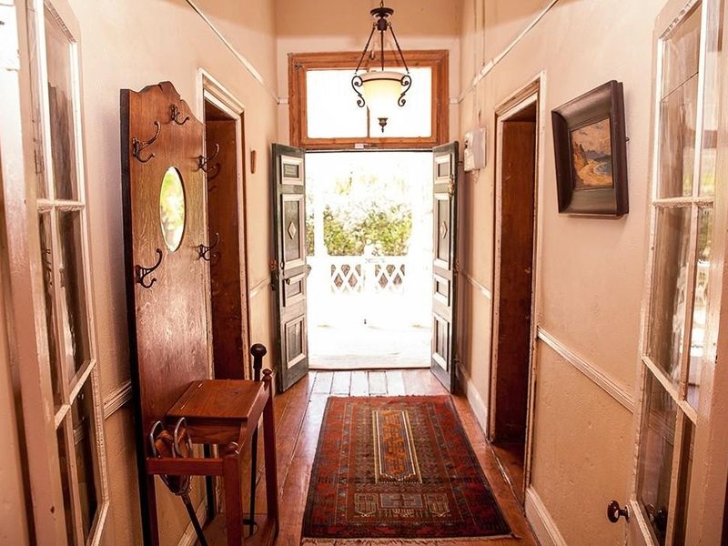 A traditional hallway featuring timber flooring, wainscoting, and classic multi-pane glass doors leading to an exterior entrance.