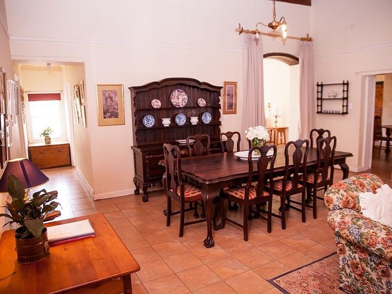 A spacious dining room featuring tiled flooring, high ceilings, and an elegant archway leading to adjacent living areas.