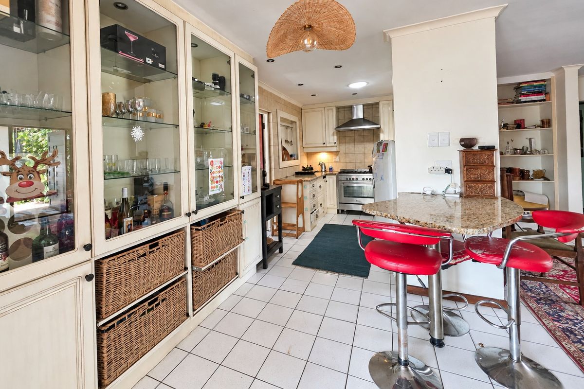 A functional kitchen featuring built-in cabinetry, granite breakfast bar, stainless steel gas stove, and tiled flooring with ample storage space.