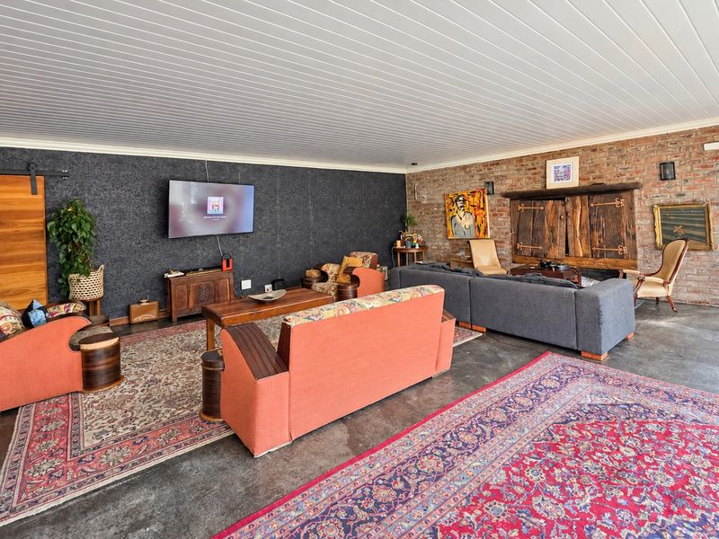 Spacious living area featuring a combination of exposed brick and textured feature walls, concrete flooring, and a tongue and groove ceiling.
