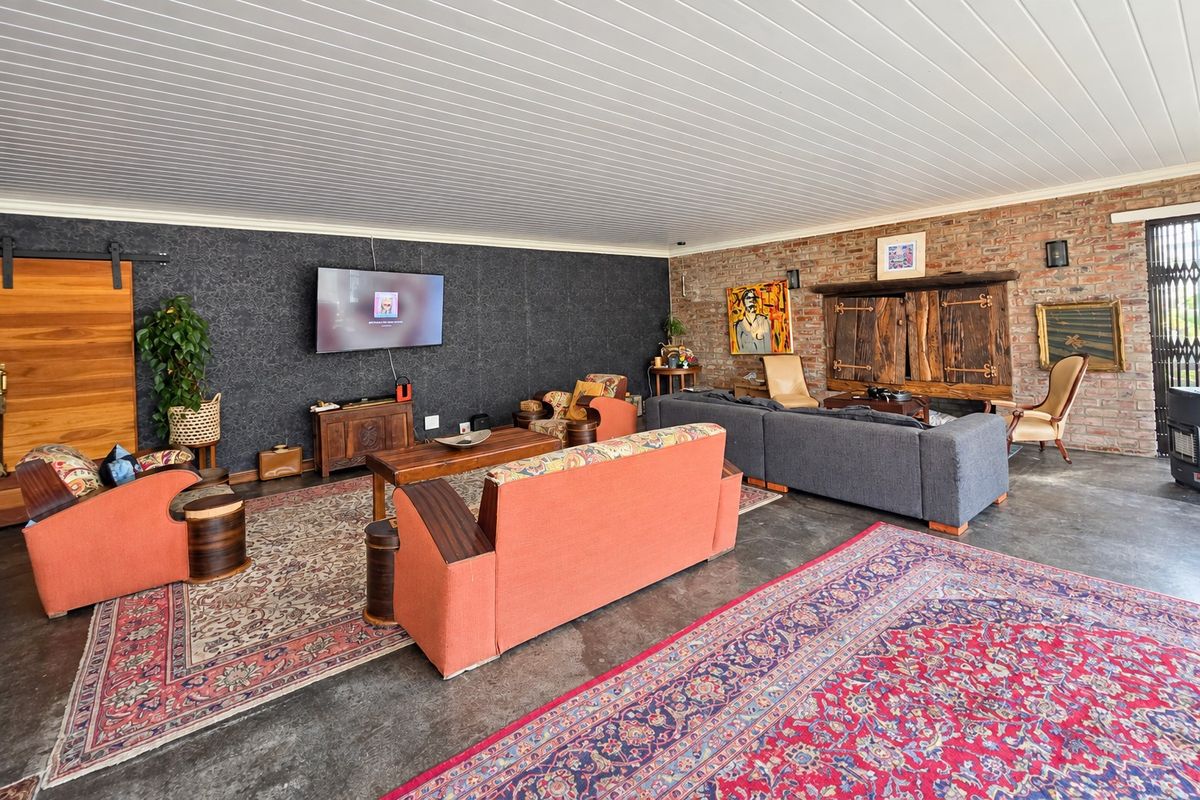 Spacious living area featuring a combination of exposed brick and textured feature walls, concrete flooring, and a tongue and groove ceiling.