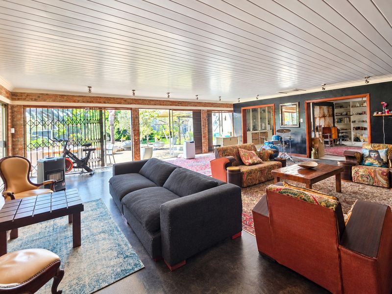 Spacious living area featuring exposed brick walls, large sliding glass doors with security gates, and a distinctive tongue and groove ceiling.