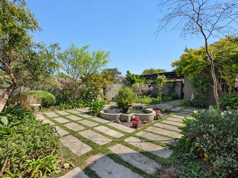 A well-maintained garden featuring stone paving, a central water feature, and lush landscaping, providing a serene outdoor space.