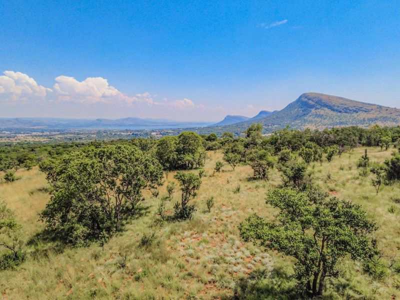 An elevated aerial view showcasing the expansive natural landscape, indigenous vegetation, and scenic mountain vistas surrounding the vacant residential property.