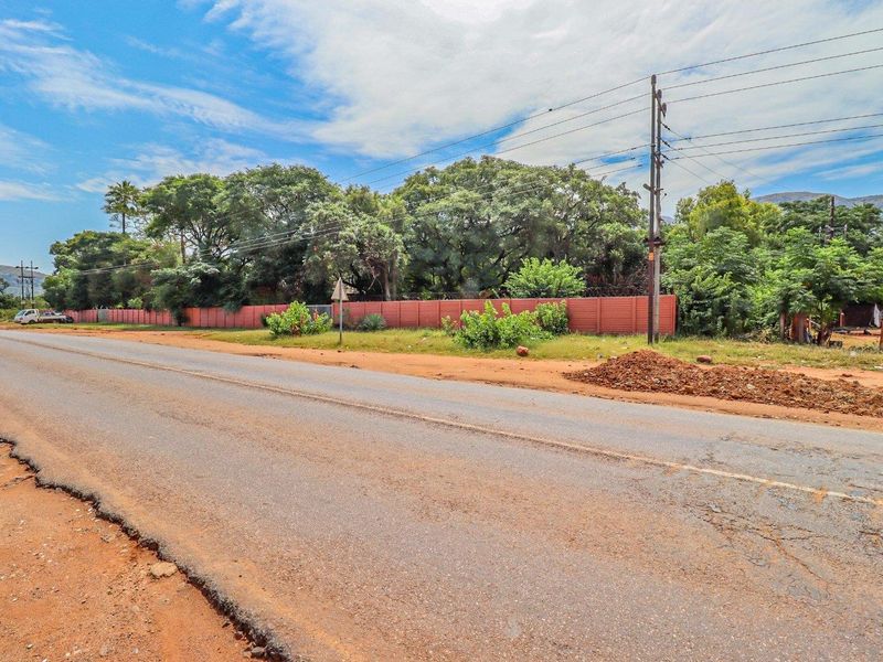 A street-level view of the vacant residential land, featuring perimeter fencing, mature trees, and accessible utility infrastructure along the road frontage.